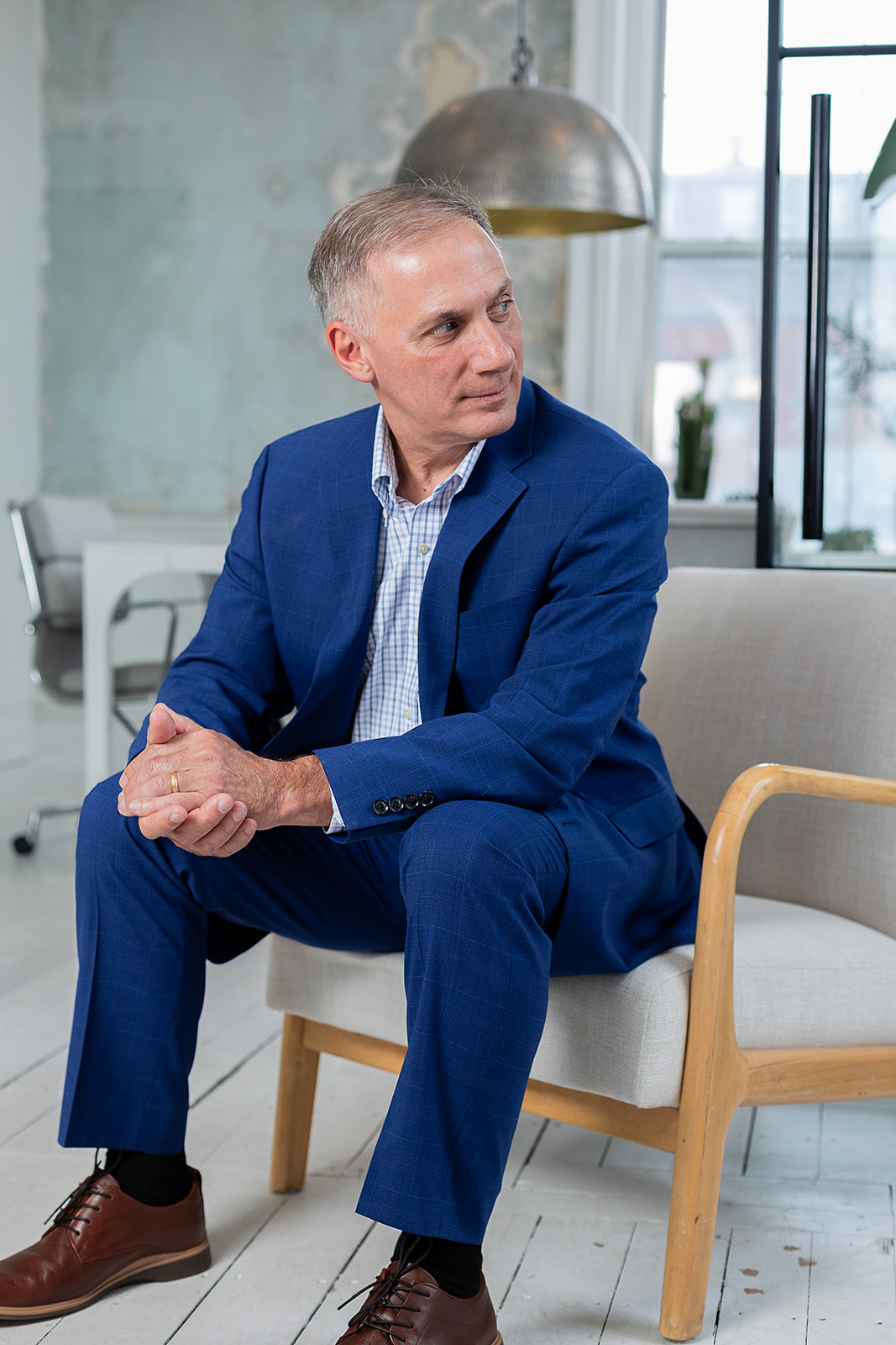 Posed shot of insurance agent seated, rubbing hands together and looking off frame to the right. 