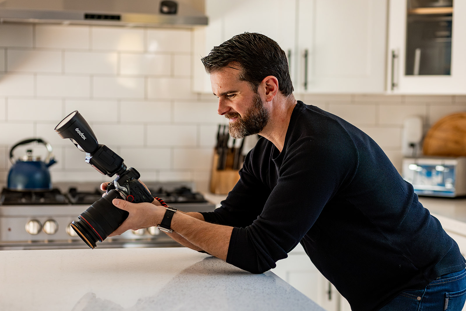 photographer leaning against kitchen camera admiring back of camera preview