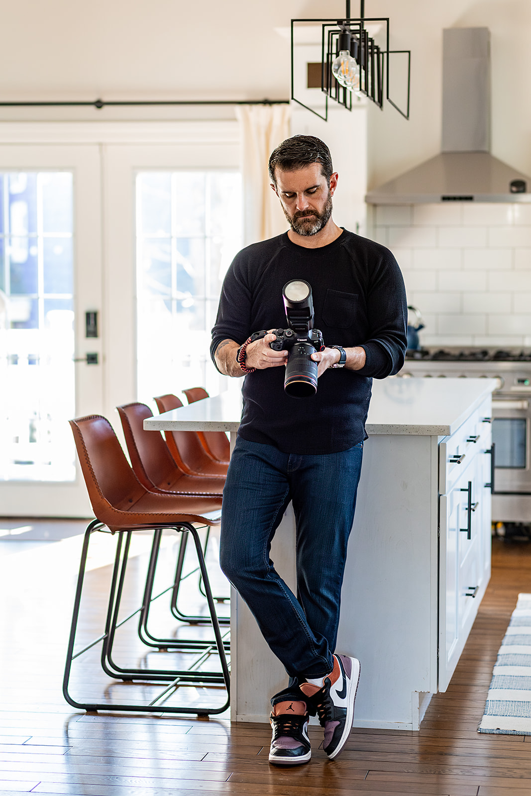 photographer leaning against counter in kitchen looking at camera. 