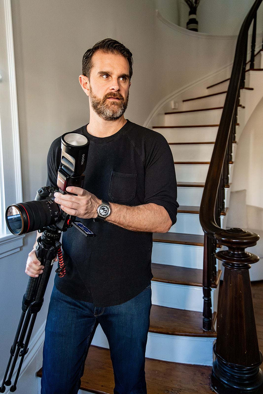 Photographer carrying camera and tripod down stairs. 