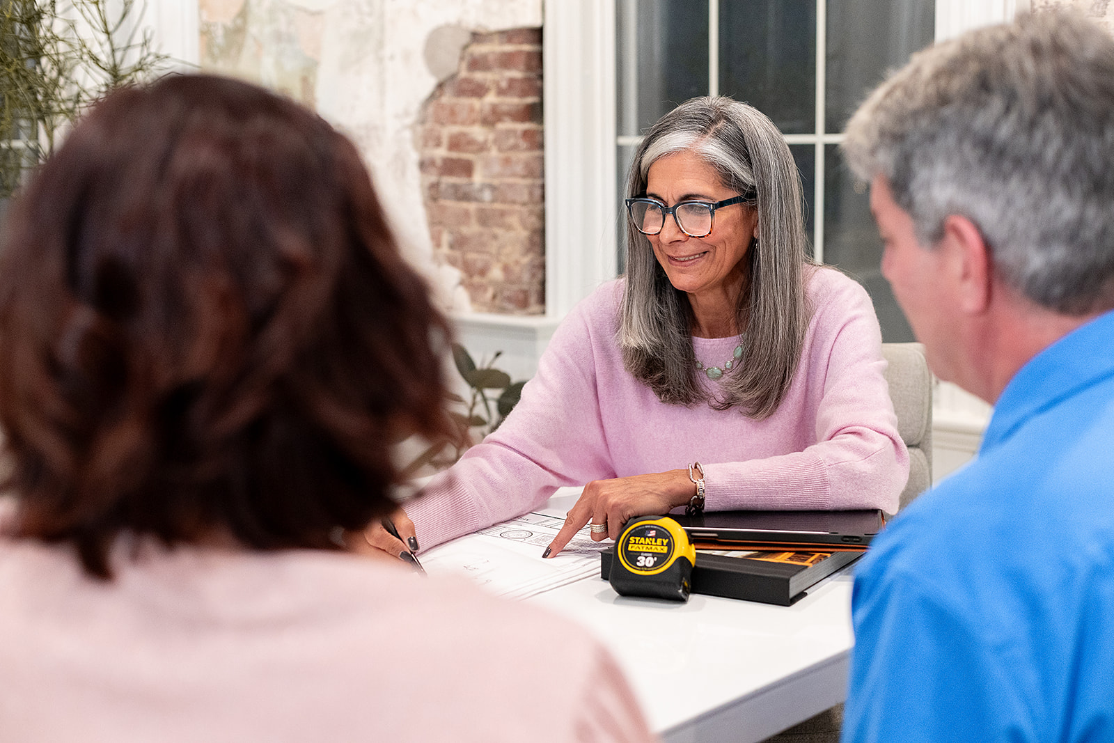 Mary holding a consultation with a couple about their upcoming kitchen remodel.