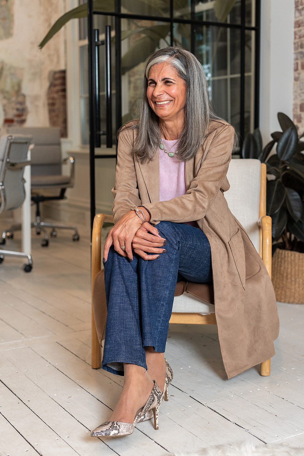 Photo of Mary sitting in chair casually, smiling at someone out of camera frame. 