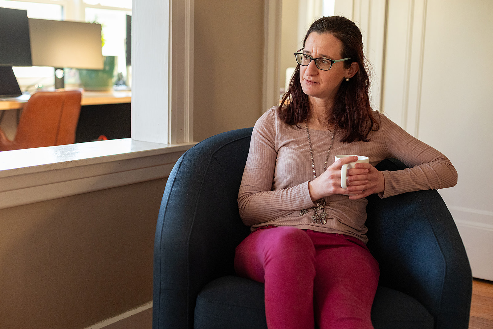 Photo of home organizer, Shira, holding a coffee mug and sitting in a comfy chair